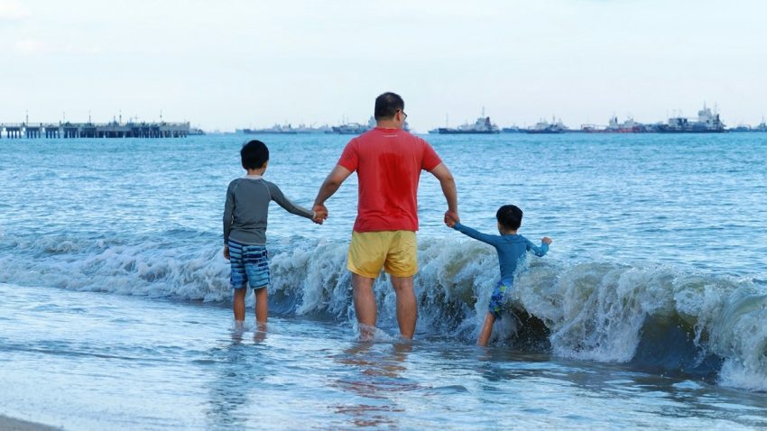 Father and two sons walking into the ocean